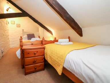 A bedroom with two single beds a wooden nightstand and exposed ceiling beams at Apple Loft in Lostwithiel
