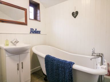 A bathroom with a freestanding bathtub and a sink cabinet with a mirror above at Apple Loft in Lostwithiel