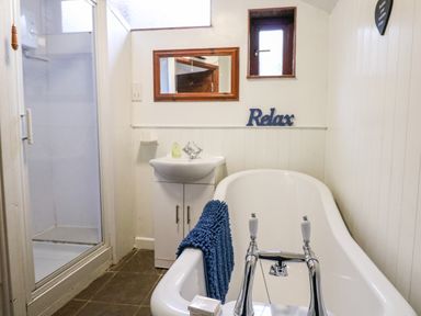 A bathroom with a bathtub a shower a sink and a mirror at Apple Loft in Lostwithiel