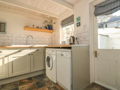 A kitchen with appliances under the counter and a door leading outside at Haven in Porthleven