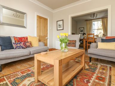 A living room with sofas pillows table and a vase with flowers at Haven in Porthleven