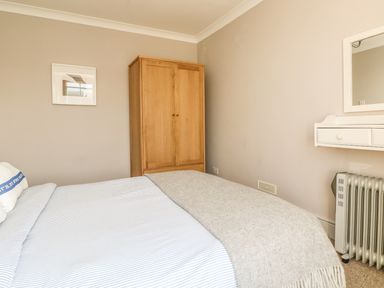 A bedroom with a bed a wooden wardrobe a wall mirror and a heater at Haven in Porthleven