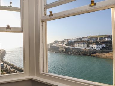 A view of a coastal village and water through a double window at Haven in Porthleven