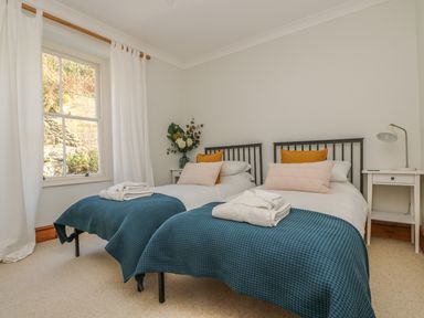 A bedroom with two single beds side by side with blue covers and white towels on top at Haven in Porthleven