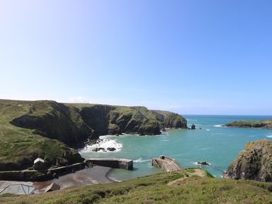 A coastal scene with cliffs a small harbor and stone piers at Cockle Island Cottage in Porthallow