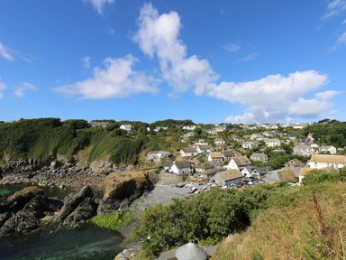 Coastal village with houses on a hillside near rocky shore and water at Cockle Island Cottage in Porthallow
