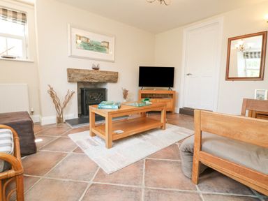 A living room with a wooden coffee table a television and a fireplace at Rose Villa in Newlyn