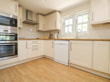 A kitchen with white cabinets stainless steel oven and microwave wooden countertop and hardwood floor at Rose Villa in Newlyn