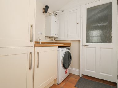 A laundry room with washing machine cabinets countertop boiler and a door at Rose Villa in Newlyn