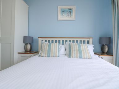 A bed with pillows and side tables with lamps in a bedroom at Rose Villa in Newlyn
