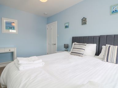 A bedroom with a bed with striped pillows and folded towels on the bed at Rose Villa in Newlyn