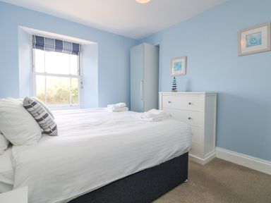 A bedroom with a bed a window a white chest of drawers and a wardrobe at Rose Villa in Newlyn
