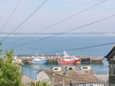 A harbor with fishing boats docked near residential houses by the sea at Rose Villa in Newlyn