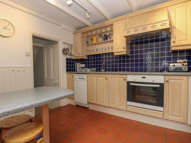 A kitchen with wooden cabinets blue tiled backsplash and appliances at Lookout in Mousehole