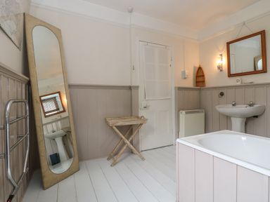A bathroom with a bathtub sink mirror standing full length mirror and wooden folding tray at Lookout in Mousehole