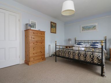 A bedroom with a metal bed a wooden chest of drawers and a bedside table at Lookout in Mousehole