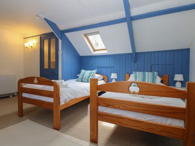 A bedroom with two wooden single beds and striped pillows at Lookout in Mousehole