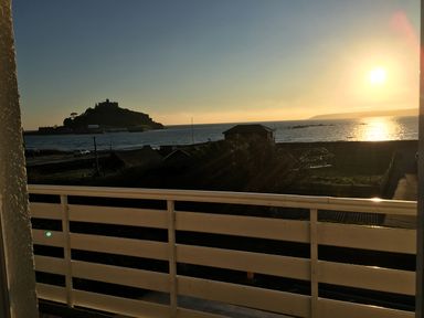 A balcony overlooking the sea with an island and a building in the distance at Sea Breeze in Marazion