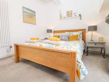 A bedroom with a wooden bed and bedside tables with lamps at Sea Breeze in Marazion
