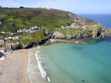 A coastal scene with a sandy beach cliffs and houses on a hillside overlooking the ocean at Mithian Cottage in St Agnes