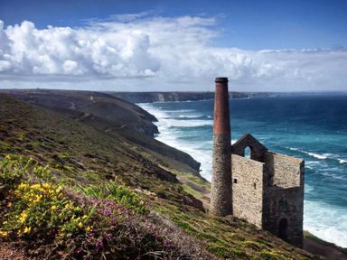 A coastal landscape with an old stone chimney and building ruins near the ocean at Mithian Cottage in St Agnes