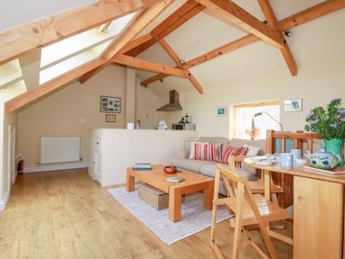 A living room with a sofa, coffee table, and dining area at Mithian Cottage in St Agnes