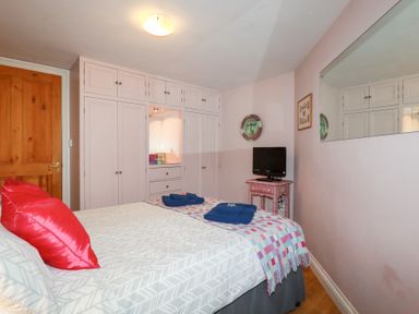 A bedroom with a bed and wardrobe at Mithian Cottage in St Agnes