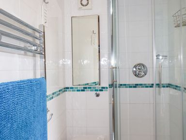 A bathroom with a shower enclosure and a blue towel at Mithian Cottage in St Agnes
