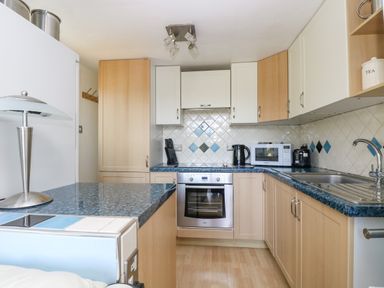 A kitchen with wooden cabinets a stainless steel oven microwave kettle and toaster at Respryn Mevagissey