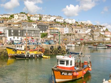 A harbor with fishing boats in the water and houses on a hillside in the background at Respryn Mevagissey