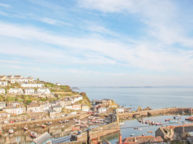 A coastal village with houses on a hillside overlooking a harbor with boats in Mevagissey