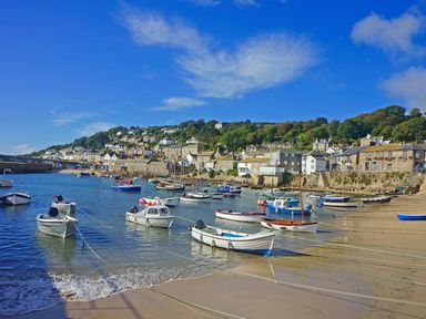 A harbor with boats tied to the shore and houses on a hillside at Calac Cottage in Mousehole