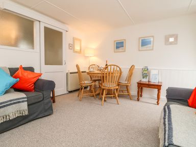 A sitting area with two sofas and a wooden dining table with chairs at Calac Cottage in Mousehole