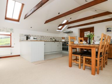 A kitchen and dining area with wooden beams and skylights at Castle Dore Barn in Fowey