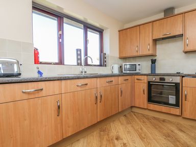 A kitchen with wooden cabinets a countertop microwave oven toaster and a kettle at Surfside in Marazion