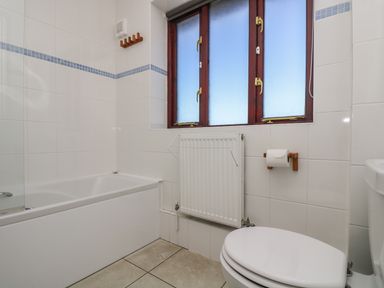 A bathroom with a bathtub toilet radiator and frosted windows at Surfside in Marazion