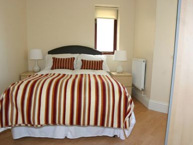 A bedroom with a bed covered in a striped blanket and two lamps on bedside tables at Sea Shore in Marazion