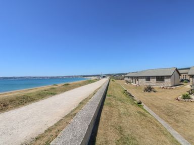 A coastal path with a seawall along the shore and stone cottages on the right at Sea Shore in Marazion