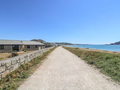A path along the coast with stone buildings on the left and the sea on the right at Sea Shore in Marazion