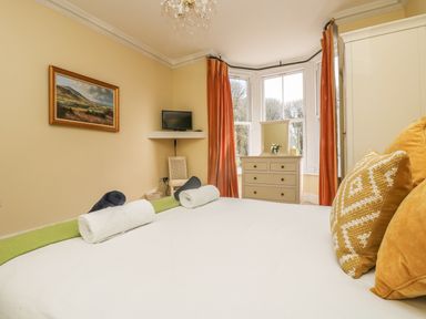 A bedroom with a bed with rolled towels a dresser with a mirror and a window at Boskednan Wartha in Penzance