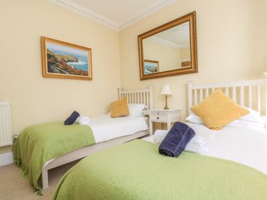 A bedroom with two single beds green throws and yellow pillows at Boskednan Wartha in Penzance