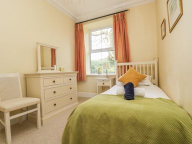 A bedroom with a single bed a bedside table a chest of drawers and a chair at Boskednan Wartha in Penzance