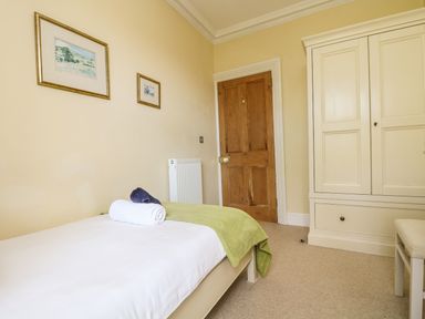 A bedroom with a bed and towel a wooden door and a white wardrobe at Boskednan Wartha in Penzance