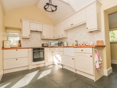 A kitchen with white cabinets wooden countertops and tiled backsplash at Boskednan Wartha in Penzance
