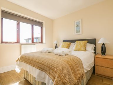 A bedroom with a double bed two bedside tables with lamps a window and a framed picture at Seashells in Marazion