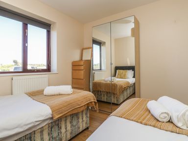 A bedroom with two single beds a chest of drawers and a mirrored wardrobe at Seashells in Marazion
