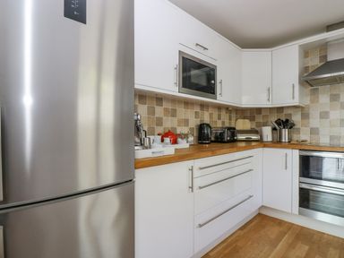 A kitchen with white cabinets wooden countertops and stainless steel appliances at Rock Pool in Downderry