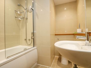 A bathroom with a bathtub shower combination and a white sink at Rock Pool in Downderry