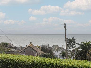 A coastal view with houses trees telephone pole and ocean at Rock Pool in Downderry