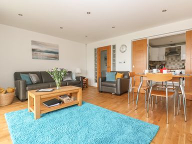 A living room with leather sofas a wooden coffee table with flowers and a dining table with chairs at Rock Pool in Downderry